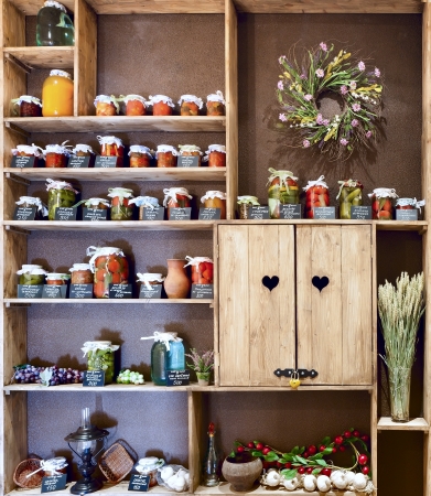 Domestic stocks with pickled vegetables in glass jars on wooden shelvesの写真素材