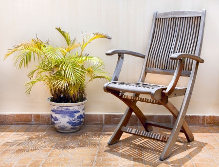 Stone terrace in the courtyard with wooden chair and palm tree in potの写真素材