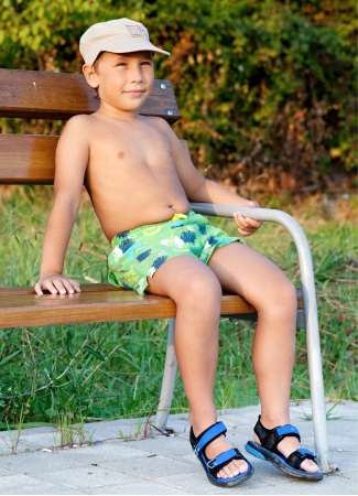 Little boy smiling and sitting on bench at parkの写真素材