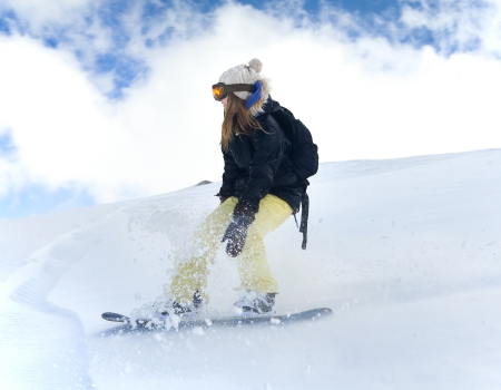 Young girl snowboarder in motion on snowboard in mountainsの写真素材