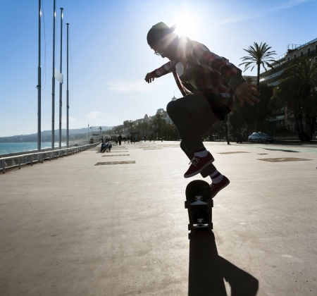 Silhouette of Skateboarder jumping in city on background of promenade and seaの写真素材