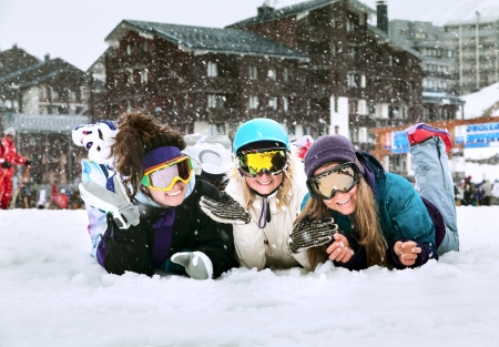 Three smiling young girls are snowboarders on the snow in mountains in French Alps the background of falling snowの写真素材