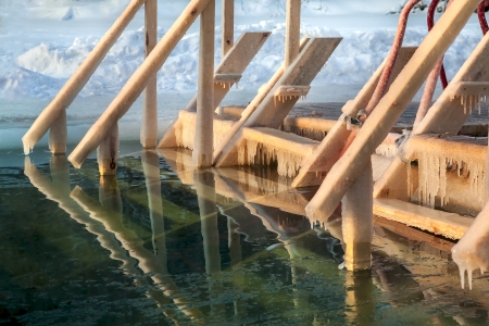 Ice-hole in Epiphany frosts. Frozen wooden ladder for descent into Ice-holeの写真素材