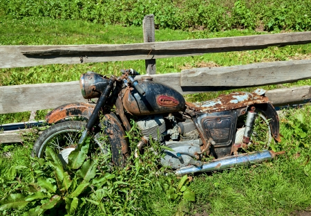 Old classic motorcycle Soviet times, standing by the fence in the villageの写真素材