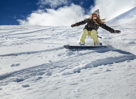Young girl snowboarder in motion on snowboard in mountainsの写真素材