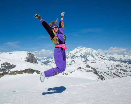 Happy woman jumping on the background of snowy mountains