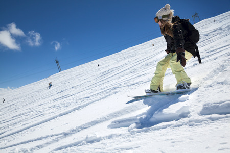 Young girl snowboarder in motion on snowboard in mountainsの写真素材