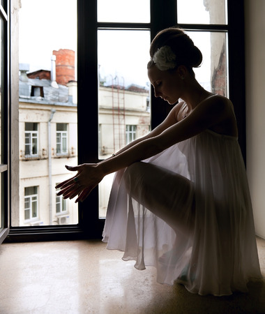 Silhouette of a beautiful thoughtful bride sitting on window sillの写真素材