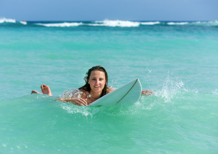 Attractive young woman on surfboard in the ocean drifting on the spotの写真素材