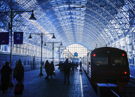 Covered railway station with trains and silhouettes of hurrying peopleのeditorial素材