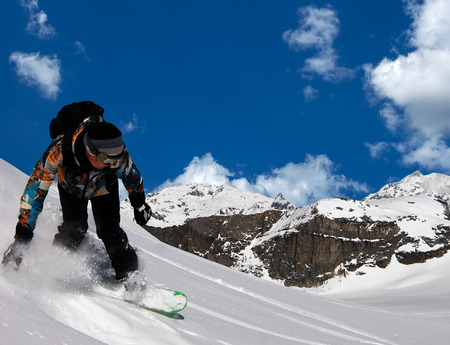Freerider snowboarder moving down in snow powder on against the blue sky and cloudsの写真素材