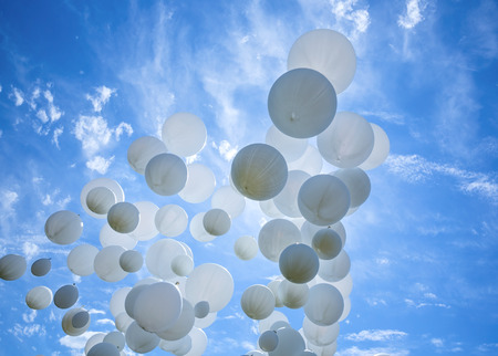 Many white balloons and celebration concept against the blue sky and cloudsの写真素材