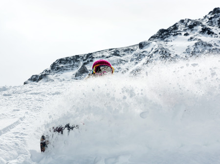 Young woman snowboarder in motion on snowboard in mountainsの写真素材