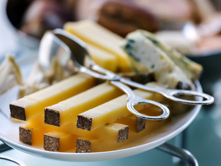 Sliced ??durum cheese on a plate and special  cutlery to capture cheese. Soft focusの写真素材