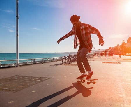 Silhouette of Skateboarder jumping in city on background of promenade and seaの写真素材