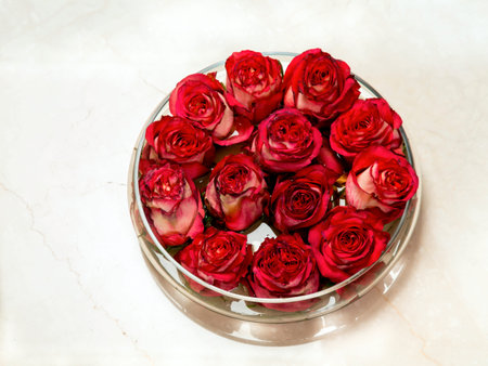 Red rosebuds in glass vase with water on the marble floor. Valentines day romantic background, top viewの写真素材