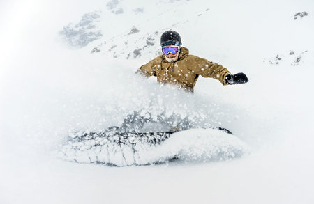 Freerider snowboarder moving down in snow powderの写真素材