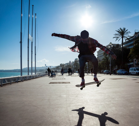 Silhouette of Skateboarder jumping in city on background of promenade and seaの写真素材