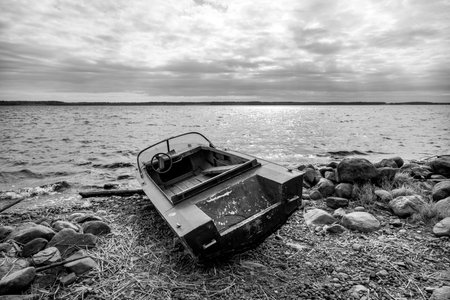 Old fishing motor boat on lake coast in Karelia. Black and white photoの写真素材