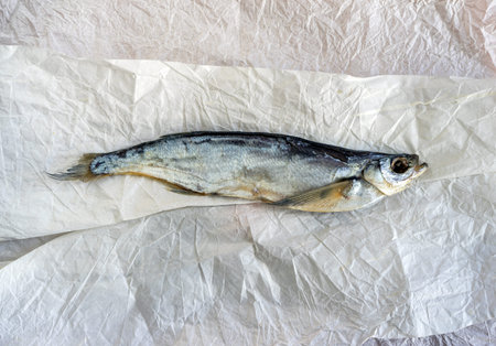 Dried river fish sabrefish on old paper closeup