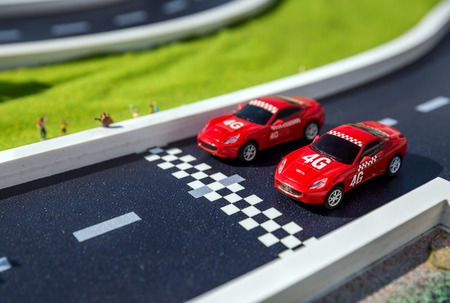 Toy sport cars on a breadboard. Two reds racing cars on race trackの写真素材