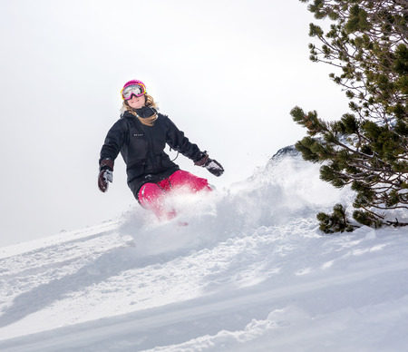 Young woman snowboarder in motion on snowboard in mountainsの写真素材
