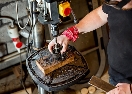 Electric drilling machine with manual pressure, a man holding a metal part and the hole is drilled. Worker holding drill for cooling in industrial oilの写真素材