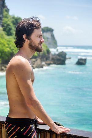 Portrait of male surfer, looking into the distance of ocean from the top places on the coastの写真素材