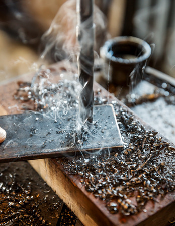 Electric drilling machine with manual pressure, a man holding a metal part and the hole is drilled, strongly pressing drill to the workpiece surfaceの写真素材