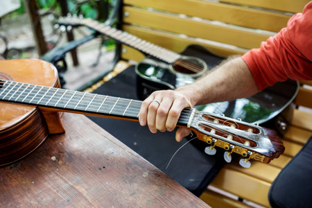 Man takes a classical acoustic guitar in the hand, lying on the wooden table