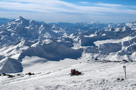 Tourists on the snowmobile quickly rise to the top on the background of beautiful scenery in the...