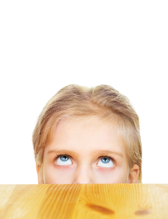 Portrait of young blonde girl looking up from under table isolated on white backgroundの写真素材