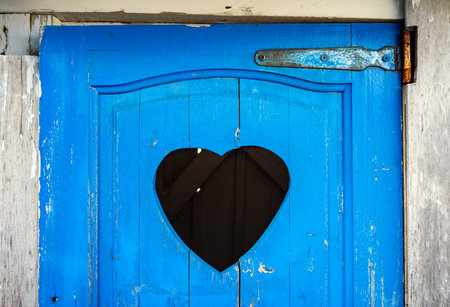 Old blue door of toilet with a heart shaped hole cut outの写真素材