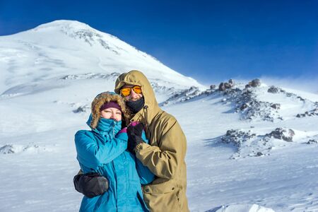 Happy young couple snowboarders on the background high mountains on the winter resortの写真素材