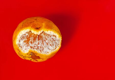 Ripe mandarin fruit peeled isolated on the red background closeupの写真素材