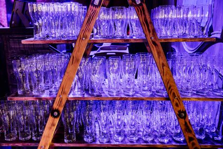 Empty glasses on shelf in restaurant. Many clear glasses on  wooden rack, standing in row close upの写真素材