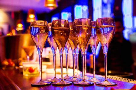 Glasses of champagne on bar counter with barman professional, which making cocktail drinks in background, soft focusの写真素材