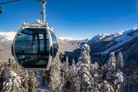 Cabin of cableway in motion closeup on rise or descent on background beautiful landscape of snowy high mountains on ski resort Rosa Khutorの写真素材