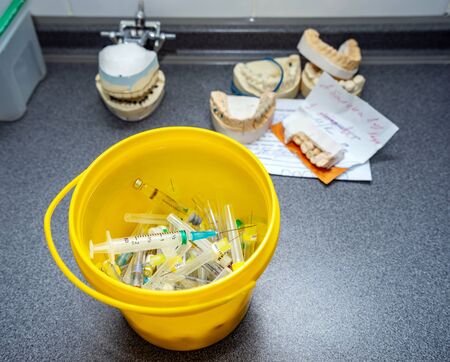 Medical waste, syringes with needles and empty vials in the trash bucket closeup.の写真素材