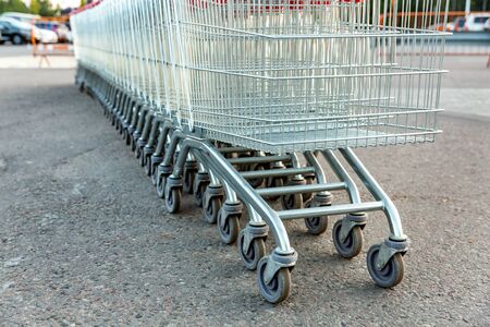 Many empty shopping carts in a row, standing on the outdoor near a supermarketの写真素材