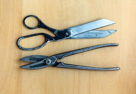 Old tailor's scissors and metal shears isolated on a wooden background closeupの写真素材