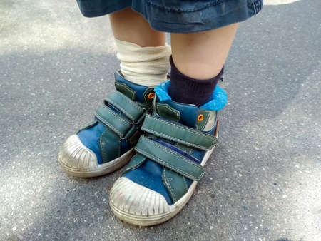 Legs of a boy in blue sneakers closeup, standing on an asphalt road during a walk. Elastic bandage on the legの写真素材