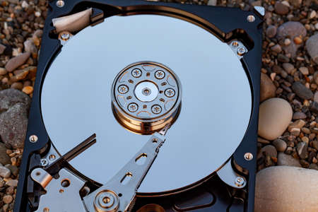 View of hard drive inside closeup against background of sea pebblesの写真素材