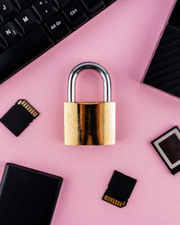 Data protection minimal concept. Flat lay setup on pink backdrop. Lock and data devices.の写真素材