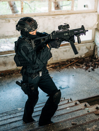 Woman as a police member of swat unit wearing a black jumpsuit and carrying UMP assault rifle....