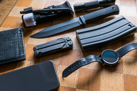 Military EDC concept on chess board background. Survival knife, M4 mag, smartwatch, smartphone, tourniquet, multitool,wallet, flashlight. Men's everday carry.の写真素材