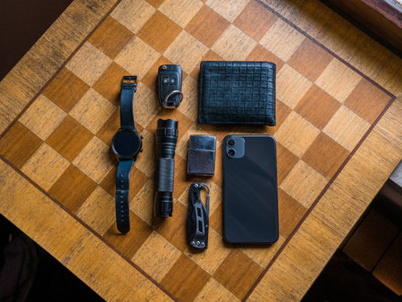 EDC setup. Concept on the wooden chess board. Everyday carry for a man. Knife, Multitool,...