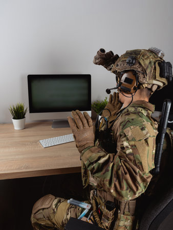 US Army special forces operator looking at the computer screen. Seal team operator in full gear.の写真素材