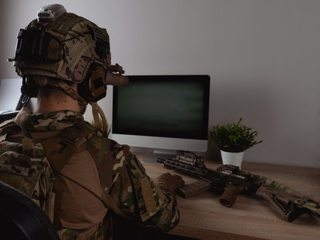 US Army special forces operator looking at the computer screen. Seal team operator in full gear.の写真素材