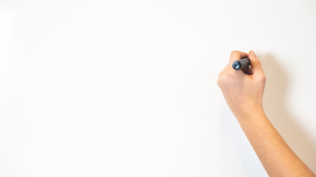 Office and business concept, hand holding or writing with black marker on the white board or backdrop.の写真素材